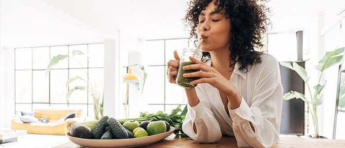 a woman enjoying a green juice, embodying the principles of clean eating and healthy living