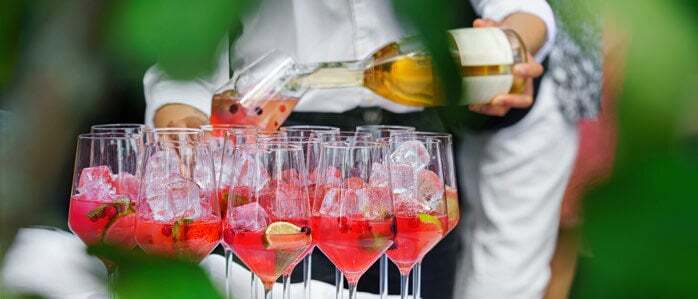 a close-up of a person pouring a wine cocktail into a glas